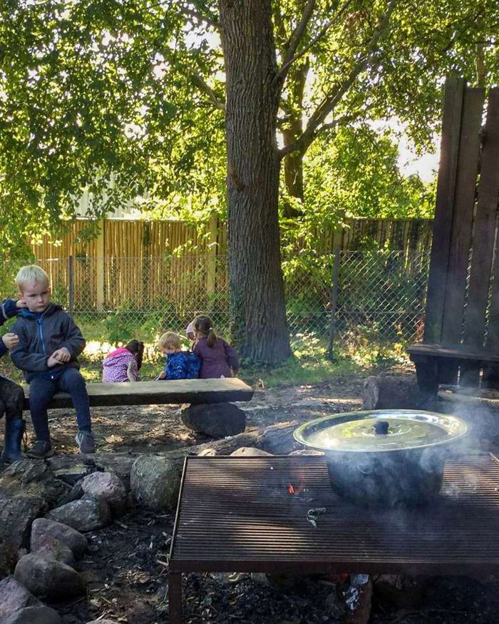 2 børn og en voksen laver mad på bål